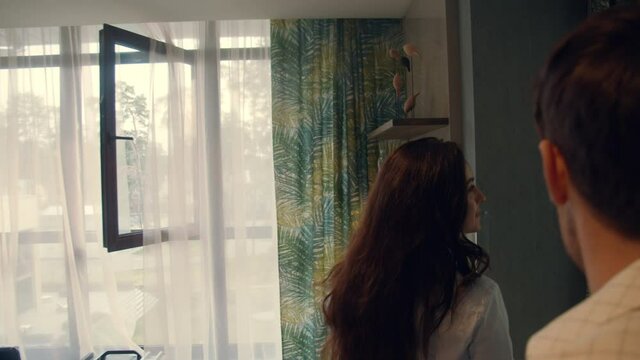 Happy couple entering hotel room. Beautiful couple falling on bed in suite.
