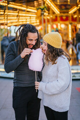 Young couple eating cotton candy at a Christmas fair