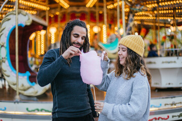 Young couple eating cotton candy at a Christmas fair