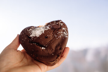 Fresh homemade chocolate chip cookies in coconut and sugar crumbs in hand against the background of the window.