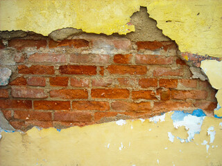 Interesting texture of broken wall and painted yellow with red bricks.