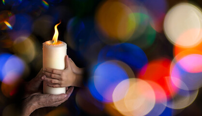 old hands and baby hands holding a candle - concept