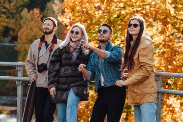 An autumn public park with yellow trees and four griends they are spending their holidays together...