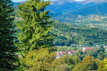 Carpathian landscape. The mountain village of Kvasy in the valley and a train in the mountains....