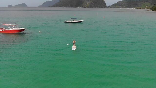 A young girl is swimming on a padelboard. Corong Corong Beach. El Nido, Palawan, Philippines
