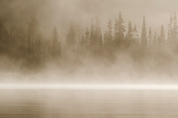 Fog on the lake hiding the forest behind it on autumn morning at lake Kesäjärvi, Kuusamo, Finland