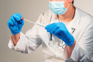 Doctor holding coronavirus swab test sample in a vial with gloves and face mask at laboratory....
