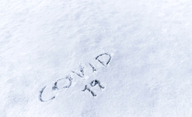 Covid 19 text written in the snow. Concept of covid-19 pandemic usable for background or poster for the 2020 winter and christmas campaign.