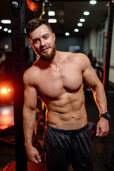 Fototapeta na wymiar Bodybuilder is posing. Beautiful sporty guy male power. Fitness muscled man without shirt on dark gym background.