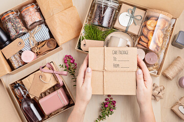 Preparing care package, seasonal gift box with coffee, cookies, candles, spices and cups