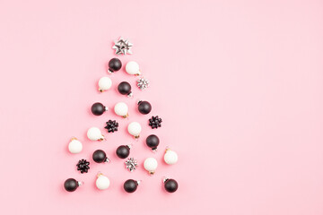 Christmas ornamets laid out in shape of Christmas tree on pink background. Winter holidays greeting card