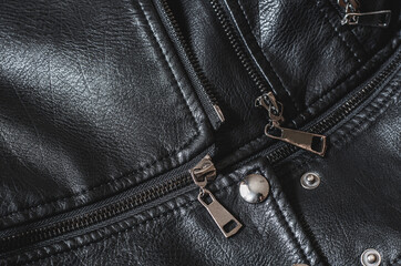 Metal zipper on a black women's jacket. Part of a leather jacket, top view. Black texture of genuine leather