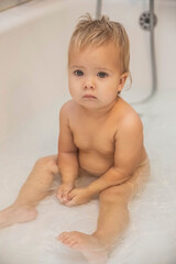 blonde baby bathes in the bathroom