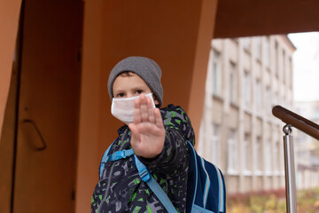 schoolboy in a protective mask shows his hand STOP
