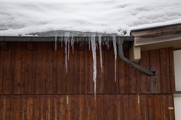 snow covered roof of a barn with icicles on the gutter