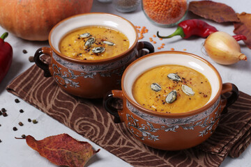 Vegetarian autumn pumpkin soup puree with red lentils in two bowls on gray background. Horizontal format. Closeup