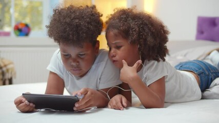 Portrait of adorable african boy and girl kids watching cartoon in earphones on digital tablet