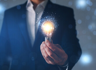 Businessman holding futuristic lightbulb with ideas and innovative technology.