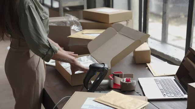 Close up view of female online store small business owner worker packing package post shipping ecommerce retail order gift in box preparing delivery parcel on table. Dropshipping shipment service.