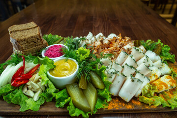 Classic slicing of different varieties of lard on a wooden background with pickles, black bread,...
