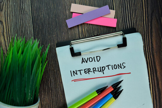 Avoid Interruptions write on a paperwork isolated on Wooden Table. Motivation or Insipiration Concept