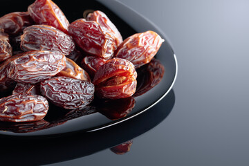 Dried sweet dates on a black plate.