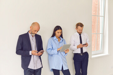 People lining up in office waiting room using modern gadgets and ignoring each other in real life