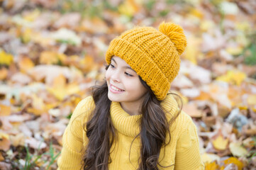happy child in casual style spend time in autumn park enjoying good weather wearing knitted hat and warm sweater, fashion