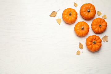 Fresh ripe pumpkins and autumn leaves on white wooden table, flat lay. Space for text