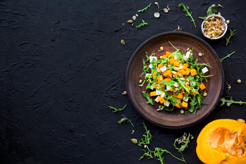 Delicious healthy pumpkin salad with arugula and cheese. Creative atmospheric decoration