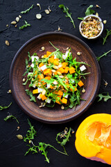 Delicious healthy pumpkin salad with arugula and cheese. Creative atmospheric decoration