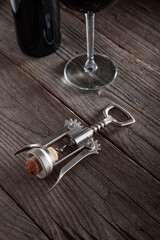 Corkscrew and a glass of wine on an old wooden table