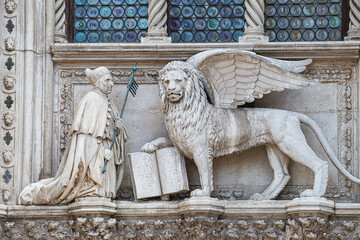 Winged lion with a Bible and a priest at Basilica San Marco in Venice, Italy, summer time, details,...