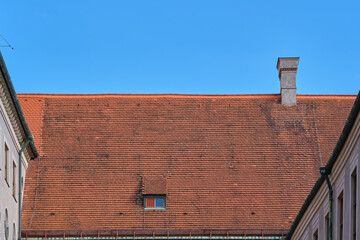 Red european roof with a small window and a chimney