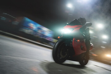 Motorbiker is riding on the night road.