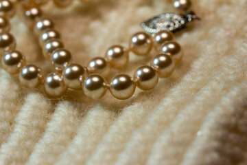 Macro abstract full frame background of cream color woolen mittens texture, adorned with a string of pearls