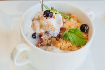 Curd dessert with berries and ice cream with mint leaves. Cottage cheese pie. Cheesecake with berries and sour cream in a white bowl