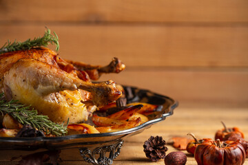 Side view of festive celebration roasted turkey with mushrooms and baked potato for Thanksgiving day on rustic wooden background with autumn harvest. Holiday concept. Traditional tasty food.