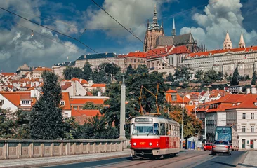 Poster Retro tram passing on Manes Bridge in Prague. Prague Castle on the background. Public transport concept. © Adsloboda