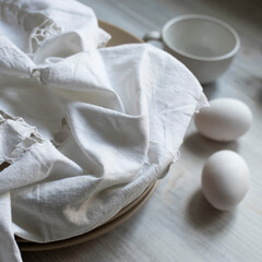 Fototapeta na wymiar a stack of plates with an embroidered crumpled napkin, two eggs and two empty tea cups on a gray wooden kitchen table