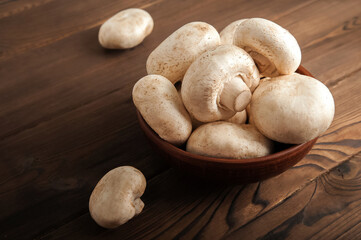 Mushrooms in a plate on a dark wooden board. Champignons and knife close up and copy space.
