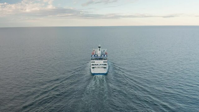 Cruise ferry ship in the ocean. Sailing toward the horizon sunset . Aerial view