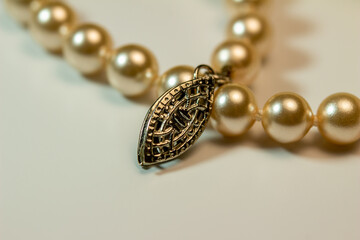 Macro abstract full frame background of cream color woolen mittens texture, adorned with a string of pearls