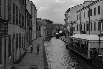 View of Comacchio canal, houses with kids riding bicycles