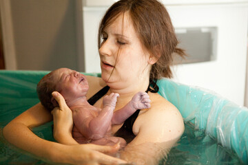 Mother Holding Newborn Baby in Birthing Pool After Home Birth