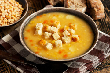 Pea soup with croutons on wooden table