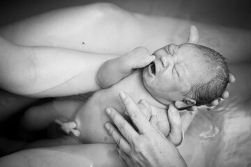 Mother Holding Newborn Baby in Birthing Pool After Home Birth