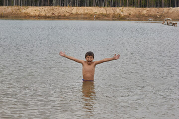 boy waist deep in the water of the lake, outdoors in the woods