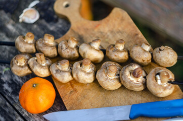 mushrooms on barbecue skewers and tangerine close-up.soft focus