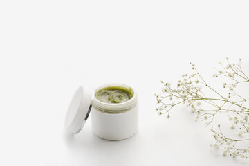 Opened plastic container with cream and flowers on a white background. face cream. herbal cream....